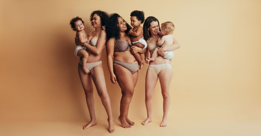 Group of multi-ethnic women standing together holding their babies
