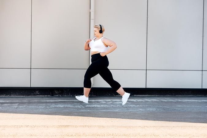 Curvy female in sportswear jogging outdoors