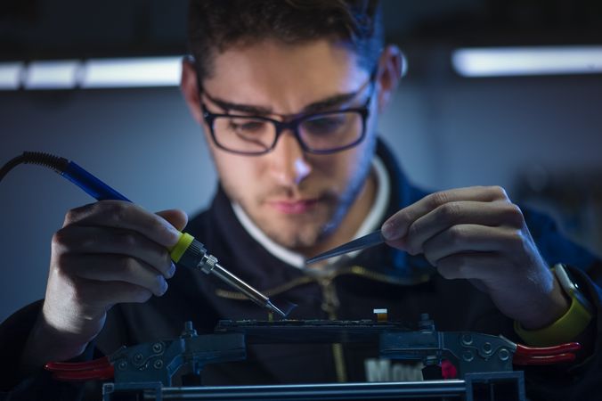Crop man fixing microchip in workshop