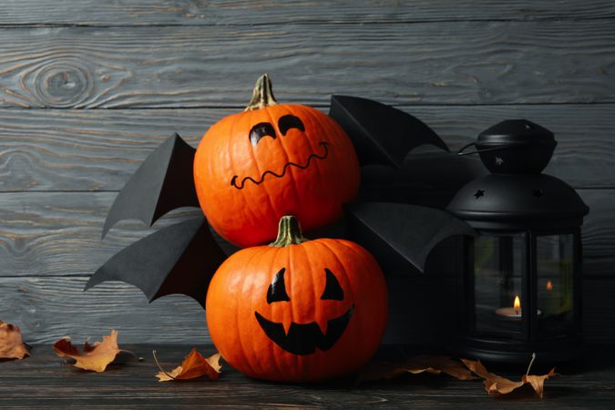 Lantern and pumpkins with wings on wooden background