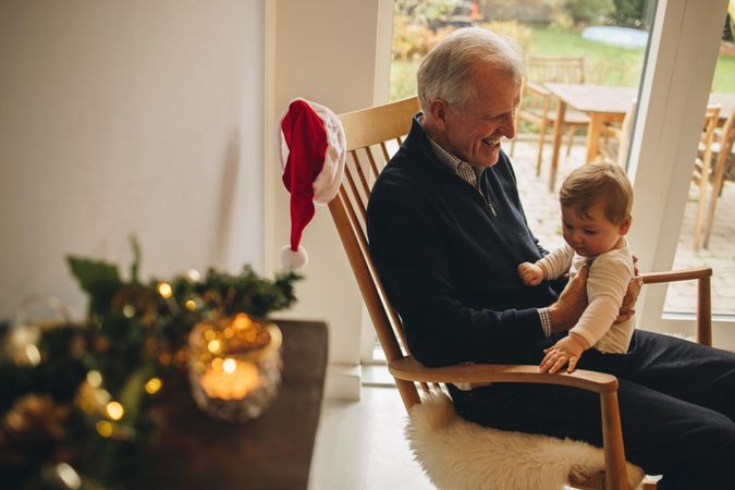 Older man sitting on chair and with his small grandson