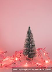 Christmas tree surrounded by fairy lights on pink background 0Vkaj5