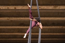 Slim woman doing yoga with aerial silks in city