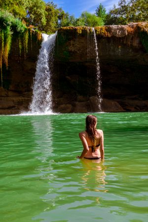 Anonymous female standing near amazing waterfall