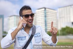 Laughing male having conversation on cell phone with city in background 5Q6Ed4