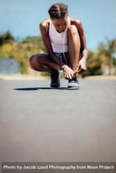 Fitness woman tying her shoelace on the road outdoors 5oNQQ0