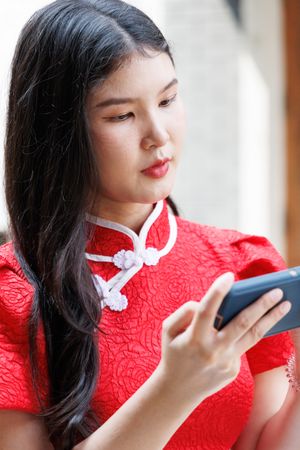 Asian woman in Chinese New Year costume using mobile phone