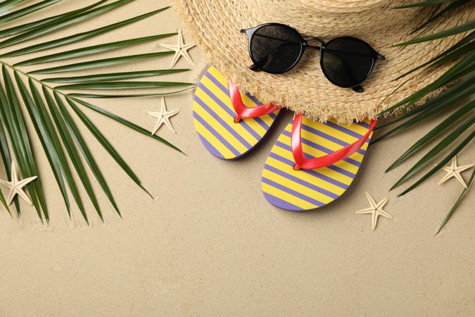 Summer vacation accessories on sea sand background, space for text