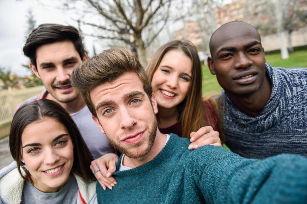 Group of friends looking down at camera and posing for selfie