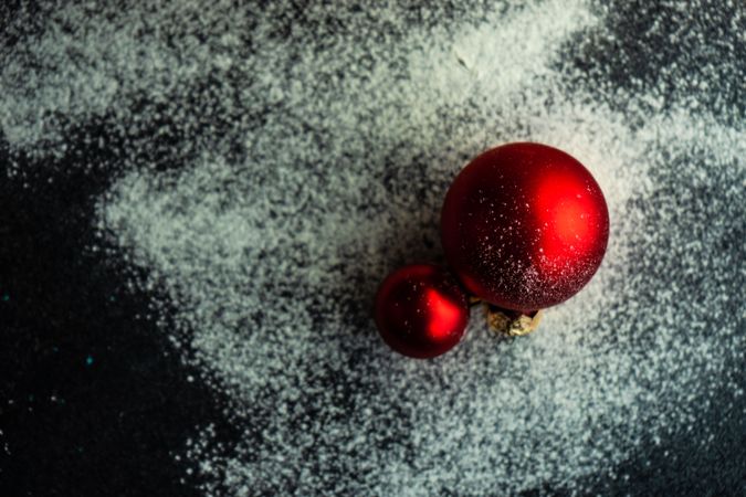 Christmas card concept with two red baubles on snowy table