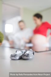 Baby shoes in foreground of pregnant woman with man 5rpqnb