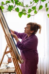 Adult woman painting canvas at home