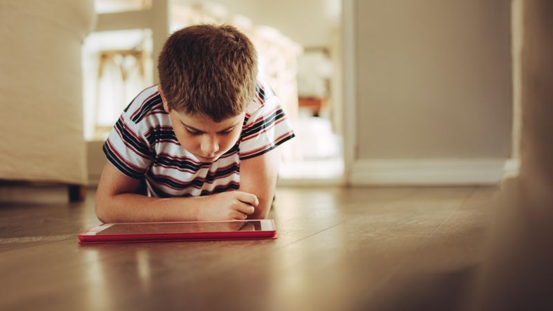Close up of a boy sitting on floor looking at a tablet pc