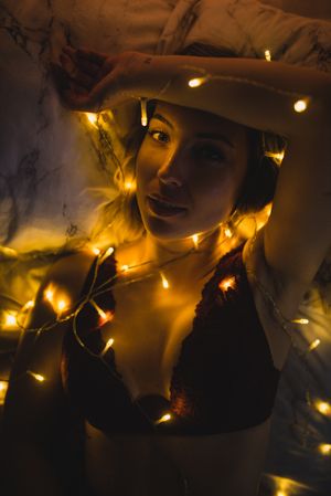 Woman lying surrounded by light garland