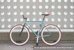 Red and green bike parked in front of patterned cement wall 5wQNWb