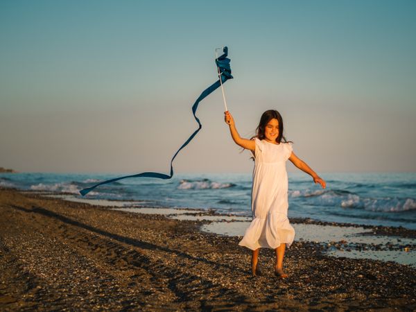 Adorable girl playing with ribbon on seaside