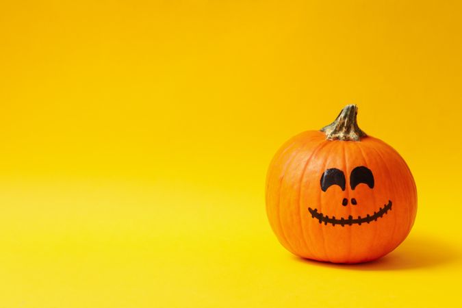 Pumpkins with smiling face on yellow background