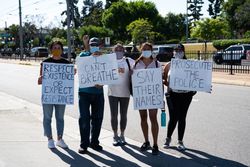 Los Angeles, CA, USA — June 7th, 2020: family poses with protests signs on city street in East LA