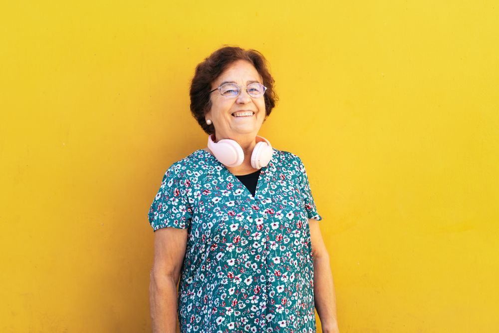 Portrait of an older woman in colorful clothes on yellow background