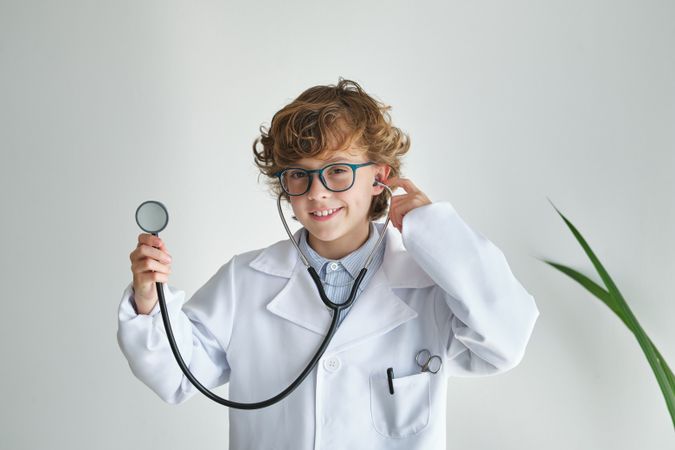 Smiling boy in medical uniform with stethoscope on white backgro