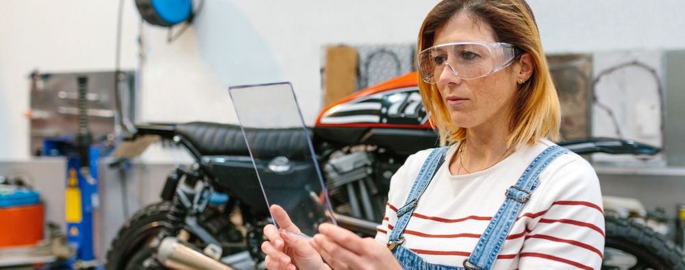 Female mechanic with security glasses holding transparent tablet