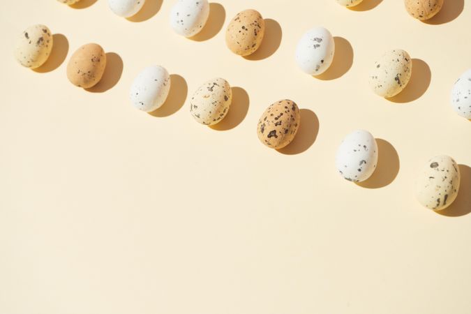 Speckled eggs  in rows on pastel yellow background