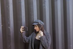 Charming Hispanic lady taking selfie near wall