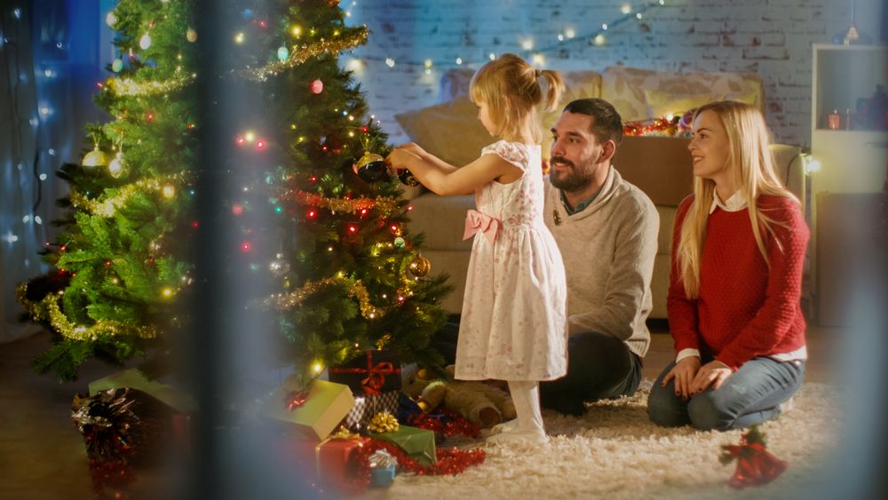 Happy Family: Father, Mother and Their Little Daughter are Decorating Christmas Tree.