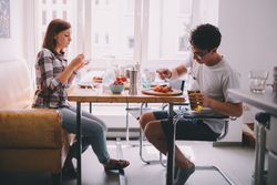 Young woman and man sitting at a breakfast table eating