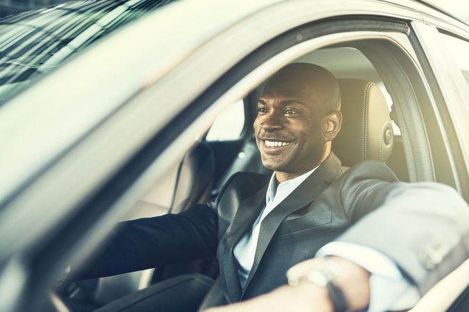 Man in business attire smiling out of a car window