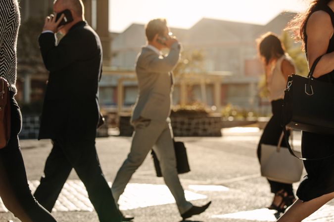 Business people busy using mobile phone while walking on street to office