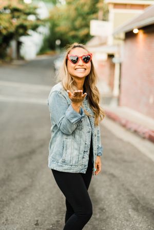 Smiling woman wearing blue denim jacket holding out open palm