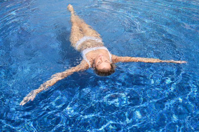 Woman with eyes closed swimming in pool
