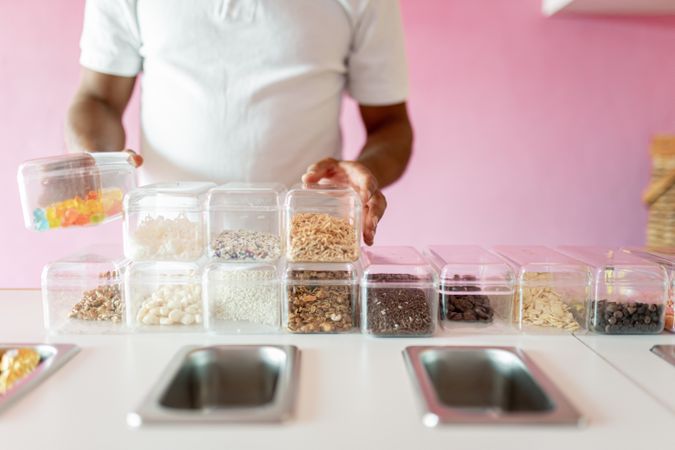 An ice-cream parlor worker is preparing all the toppings for the day on the counter
