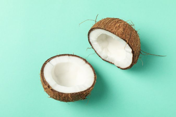 Halves of coconut on mint background, top view