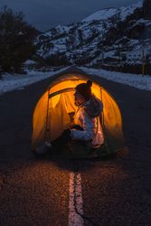 Woman sitting in open tent at twilight