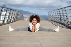 Woman leaning down into side splits on bridge with head resting on hands