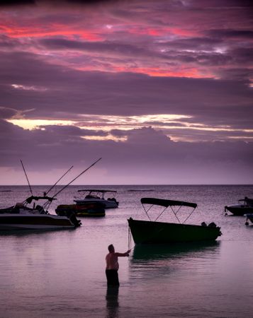 Man at dusk fishing in shallow water in the Indian Ocean
