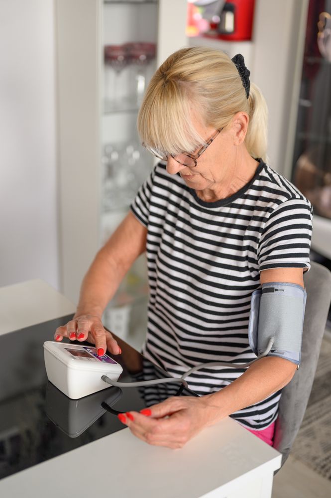 Mature woman using blood pressure monitor at home