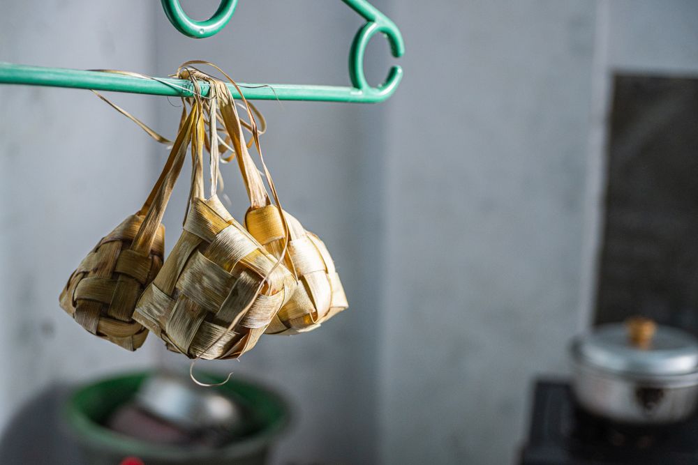Cooked ketupat hanging on a wooden rack to keep fresh and dry