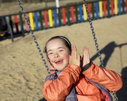 Adorable little girl swinging on playset  at park on the beach