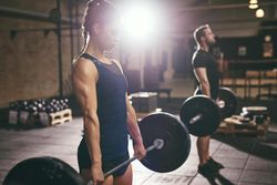 Two healthy athletes practicing weight lifting routine
