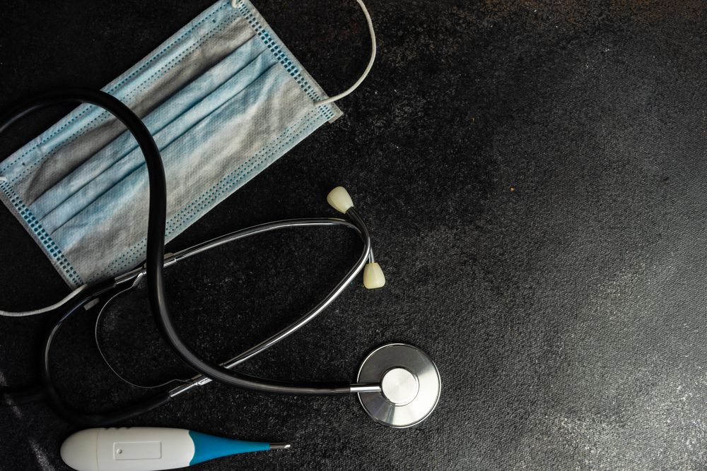 Top view of facemask, stethoscope, and digital thermometer
