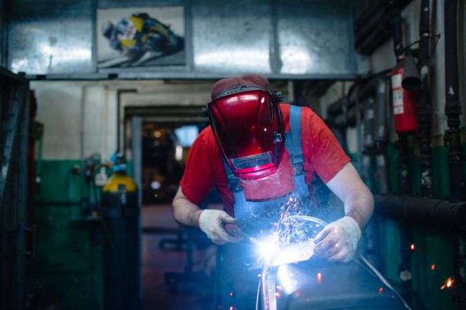 Man in red protective helmet welding metal