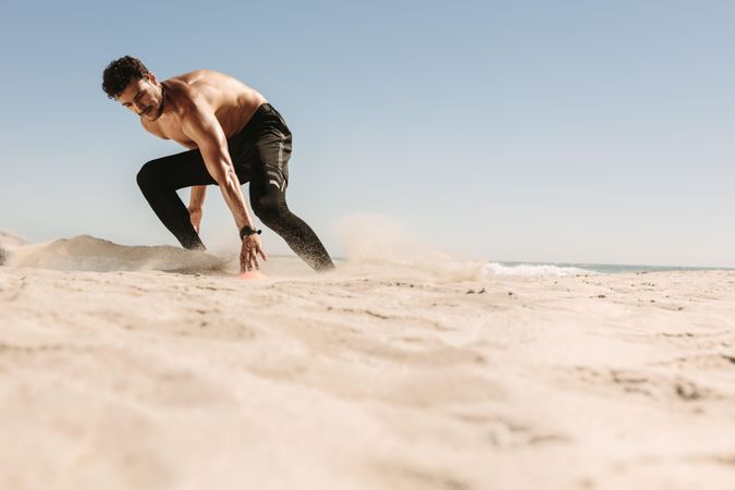 Athletic man running fast and touching marker on the sand