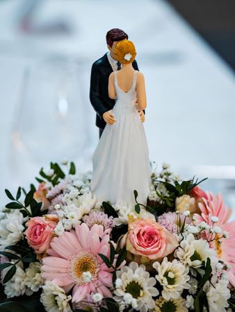 Wedding table decorations. Flowers, figurines of the bride and groom.