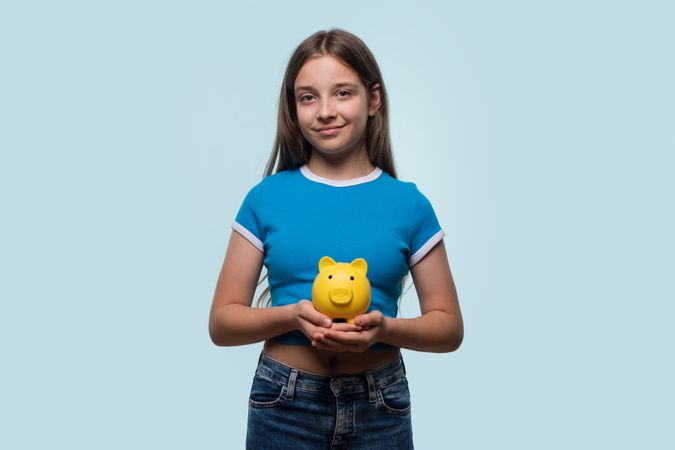 Girl smiling while holding yellow piggy bank