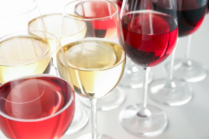 Glasses with different wine on plain background, close up