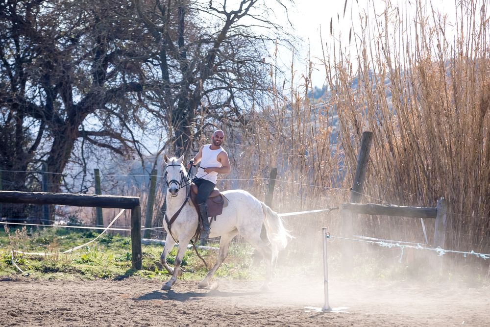 Smiling man riding horse and kicking up dust