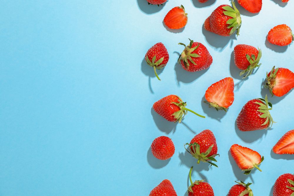 Flat lay composition with strawberries on color background, space for text. Summer sweet fruits and berries